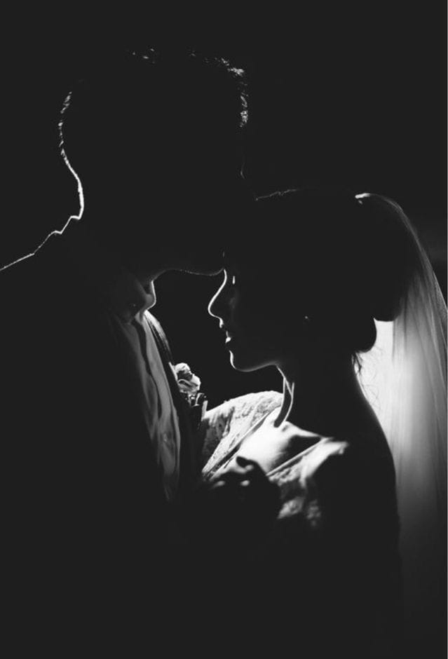 Bride and groom in silhouette beneath the veil